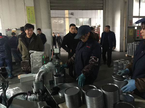 南京市印刷协会姚建秘书长（左一）与部分与会人员正在参观油墨灌装工序