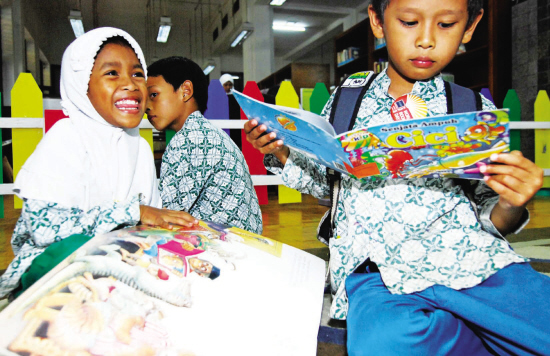 资料图：在印度尼西亚首都雅加达，两名儿童在看漫画书。